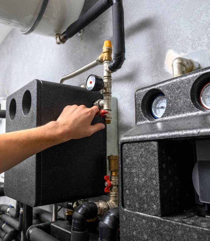 Modern electric boiler room in the house Modern electric boiler room in the house. Equipment for water heating system with automatic control unit. Close-up of a man's hand